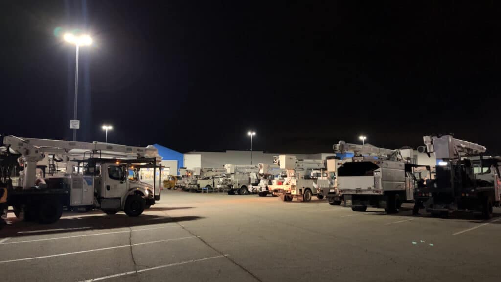 Utility bucket trucks and storm response crews staged at night for emergency power restoration deployment