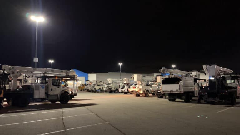 Utility bucket trucks and storm response crews staged at night for emergency power restoration deployment