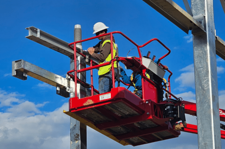 Utility workers on a lift platform performing substation site work at height on a construction pad