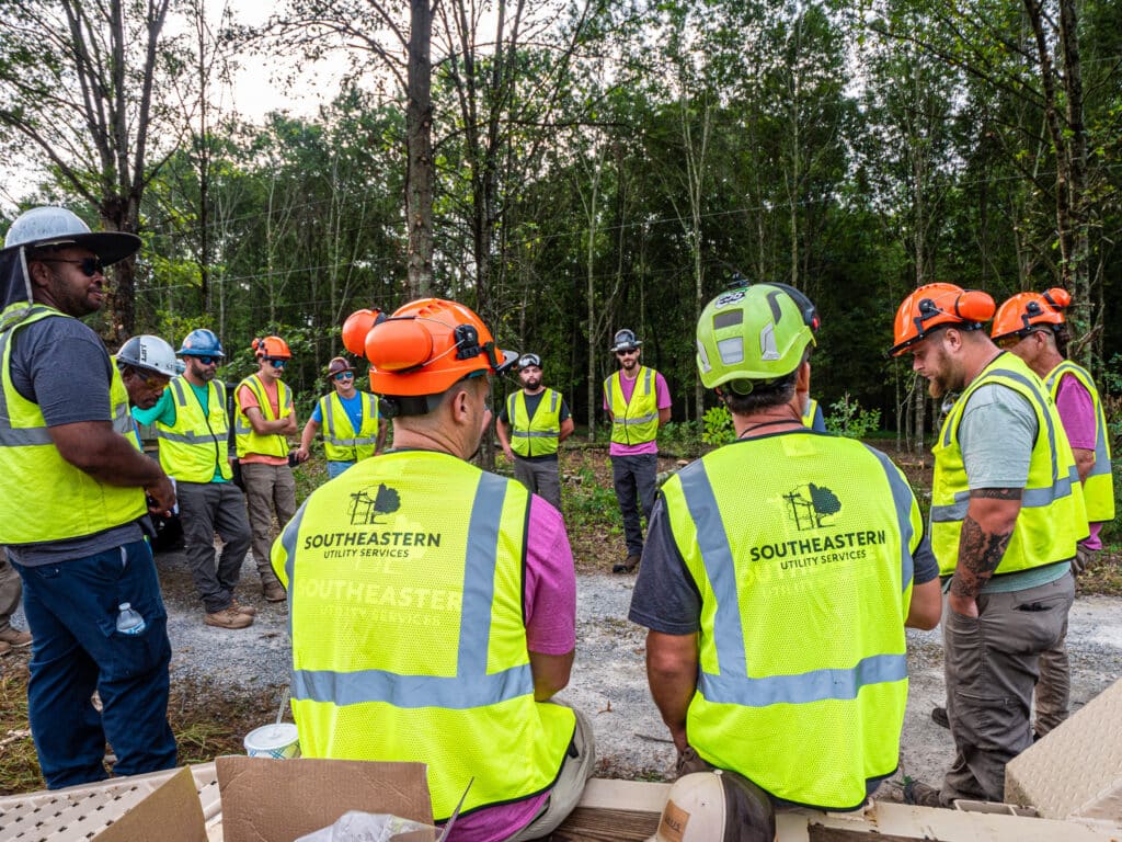 Southeastern Utility Services crew in hard hats and hi-vis vests at a job site briefing